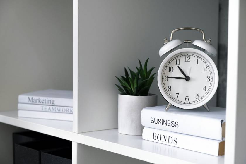 White alarm-clock with business books on shelves in office.