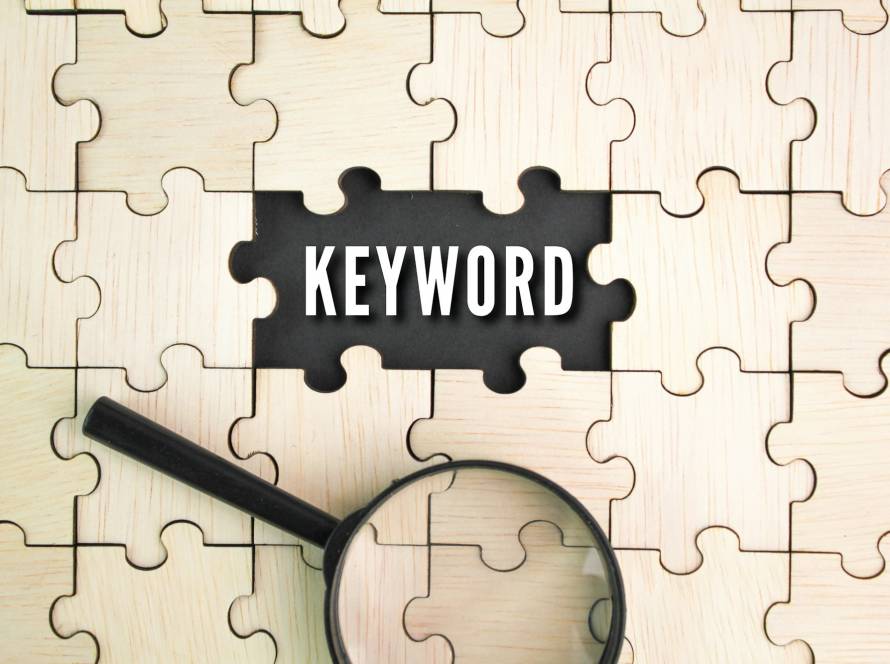 wooden puzzle and a magnifying glass with the word keyword in the middle hole of the puzzle.